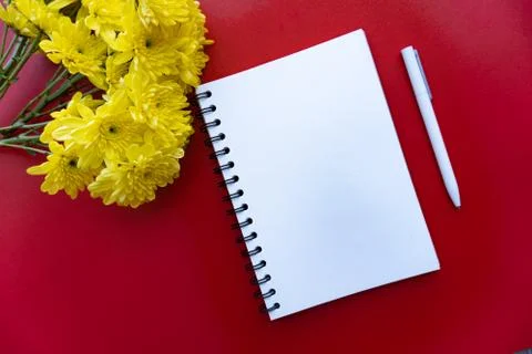 Flat lay of notebook, pen and flowers Stock Photos