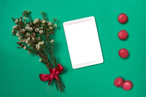 Flat lay notepad and flowers and macaroons on green background Stock Photos