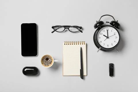 Flat lay of office essentials including a smartphone, coffee, notebook, alarm Stock Photos