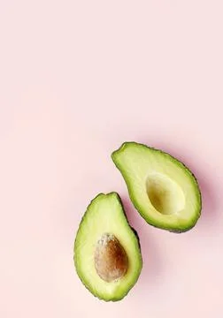 Flat lay of one halved fresh avocado over minimal pink background. Raw natura Stock Photos
