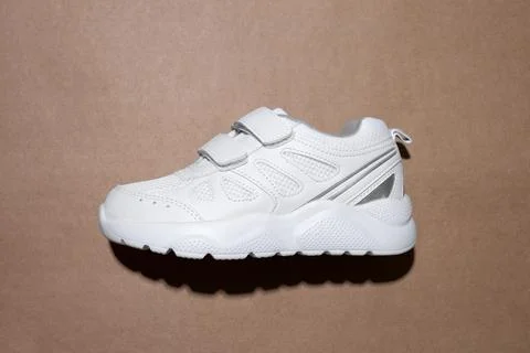 Flat lay one white child sneaker with velcro fasteners for easy slipping on t Stock Photos
