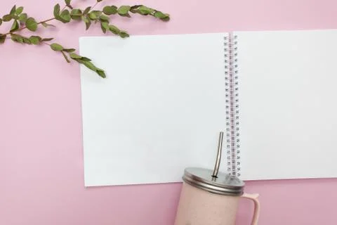 Flat lay of open notebook and cup with cap on a pink background Foto stock