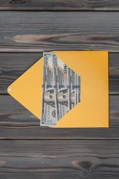 Flat lay of open yellow envelope with hundred dollars banknotes bills on grey Stock Photos