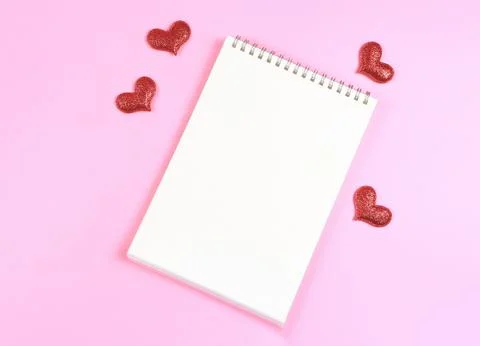 Flat lay of opened  notebook with red glitter hearts on pink background wit.. Stock Photos