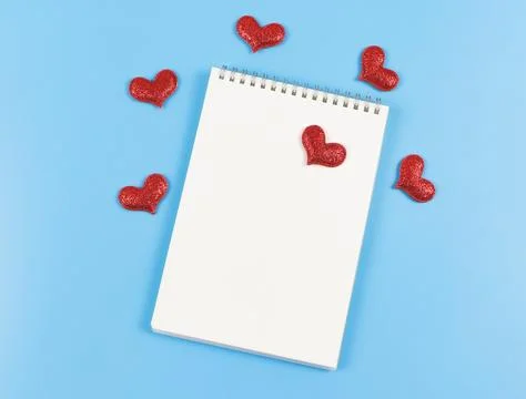 Flat lay of opened  notebook with red glitter hearts on blue  background wi.. Stock Photos