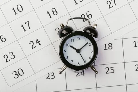 Flat lay or top view of black alarm clock with white calendar on wooden  boar Stock Photos