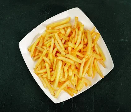 Flat lay or top view of a plate of french fres on a dark green textured Stock Photos