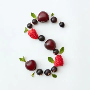 Flat lay pattern of letter S english alphabet from natural ripe berries - black Stock Photos
