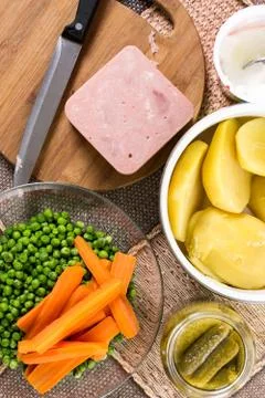 Flat lay with peeled potatoes cooked green peas carrot and ham Foto stock