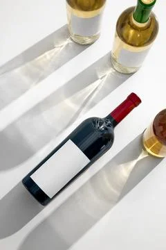 Flat-lay perspective of red wine bottle surrounded by white wine bottles Stock Photos