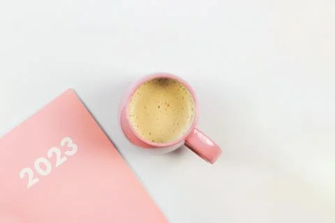 Flat lay of pink 2023 diary or planner with pink cup of coffee on white bac.. Stock Photos