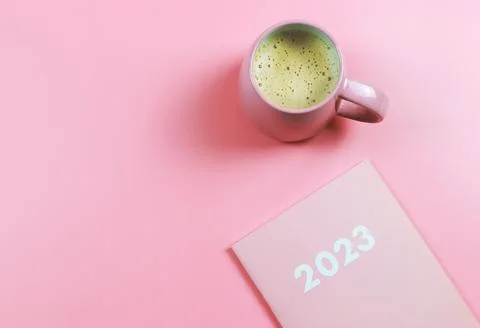 Flat lay of pink 2023 diary or planner with pink cup of coffee on pink back.. Stock Photos