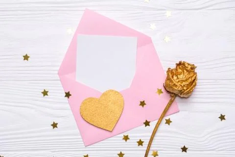 Flat lay pink envelope with a note gold rose and gold heart on white background Stock-Fotos