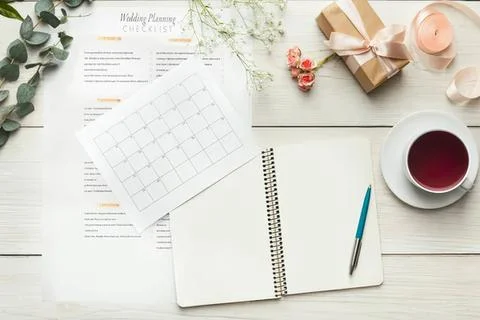 Flat lay of planner, gift, cup, and notes on white table Stock Photos