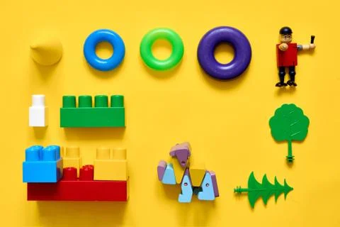 Flat lay of plastic and eco wooden toys. Developing games. Yellow background Stock Photos
