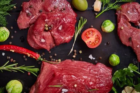 Flat lay of raw beefsteak with vegetables, herbs and spicies on metal tray Stock Photos