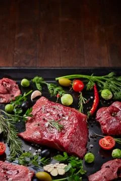 Flat lay of raw beefsteak with vegetables, herbs and spicies on metal tray Stock Photos