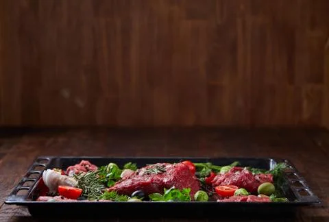 Flat lay of raw beefsteak with vegetables, herbs and spicies on metal tray Stock Photos