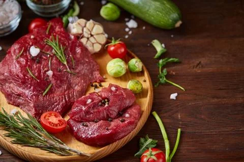 Flat lay of raw beefsteak with vegetables, herbs and spicies on metal tray Stock Photos