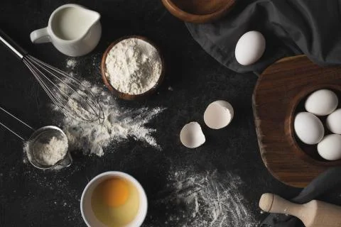 Flat lay with raw eggs, flour and various kitchen utensils for bakery isolate Stock Photos