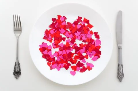 Flat lay red and pink hearts on a white plate with cutlery. Dinner woman's day Stock Photos