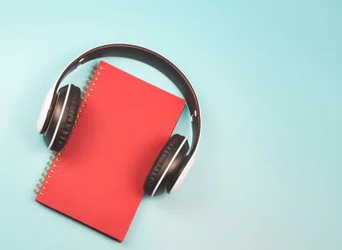 Flat lay of red notebook covered with headphones on blue background  with c.. Stock Photos