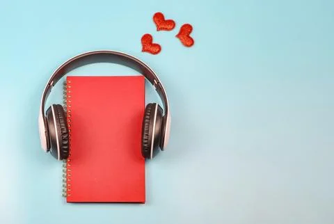Flat lay of red notebook covered with headphones on blue background decorat.. Stock Photos