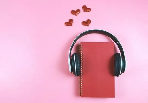 Flat lay of red notebook covered with headphones on pink  background decora.. Stock Photos