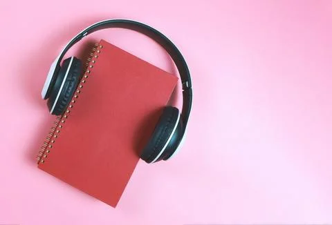 Flat lay of red notebook or  diary or planner covered with headphones on pi.. Stock Photos
