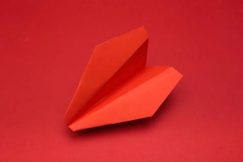Flat lay of red paper plane on red background with text space. - Image Stock Photos