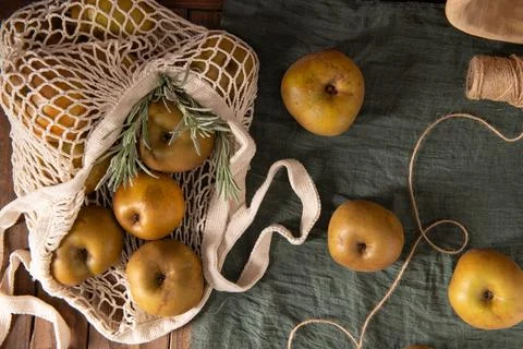 A flat lay of Reinette apples in a string bag, with a sprig of rosemary and.. Foto stock