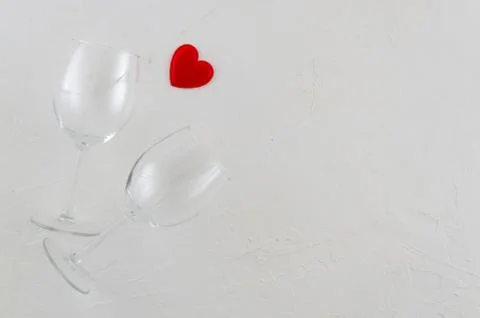 Flat lay romantic concept with two wine glasses and red heart on white isolated Stock Photos