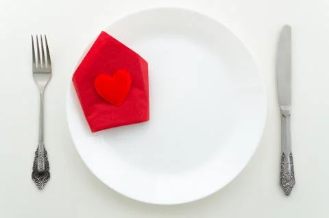 Flat lay romantic dinner proposal concept. Dish with cutlery and heart on a red Stock Photos
