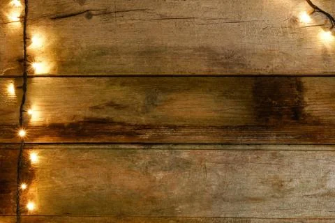 Flat lay of rustic and cracked wooden table with knots, with Christmas lights on Stock Photos