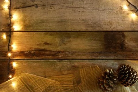Flat lay of rustic wooden table, with Christmas lights, pine cones and golden Stock Photos