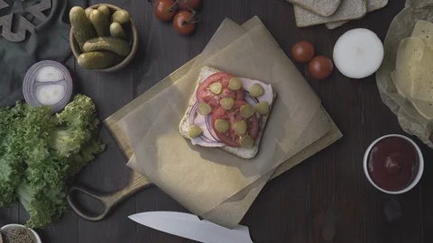 Flat lay of the sandwich with ham and vegetables on the wooden board in the beam Stock Footage 113186582