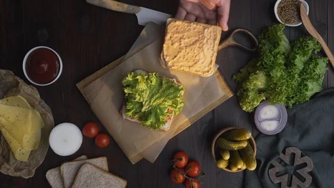 Flat lay of the sandwich with ham and salad on the wooden board in the beam of Stock Footage 113264636