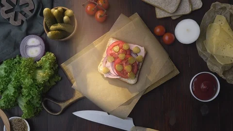 Flat lay of the sandwich with sliced ham, pickle and vegetables on the wooden Stock Footage 112599562
