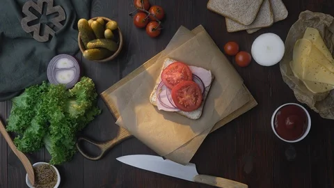 Flat lay of the sandwich with sliced ham and vegetables on the wooden board in Stock Footage 117471426
