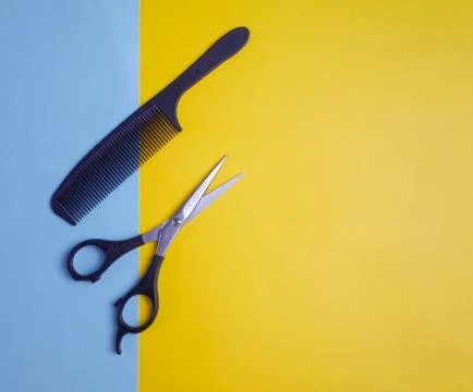 Flat lay of scissors and comb on colored paper Stock Photos