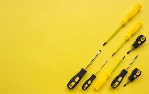 Flat lay of set of yellow and black screwdriver on yellow background. Repairi Stock Photos