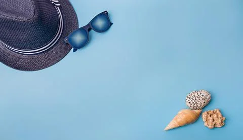 Flat lay of shells and hat on a blue background Stock Photos
