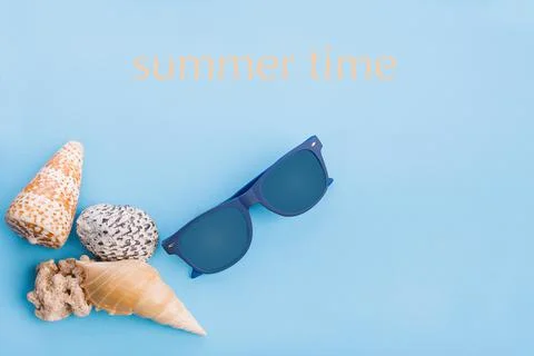 Flat lay of shells and hat on a blue background Stock Photos