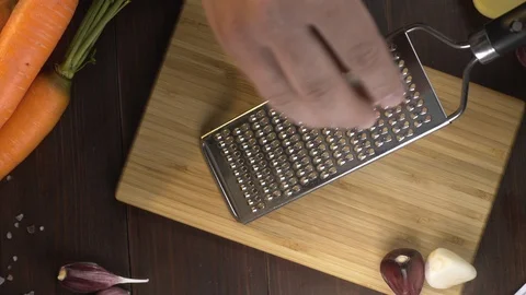 Flat lay shot: chef crates garlic on the small grater on the wooden board Stock Footage 115641539