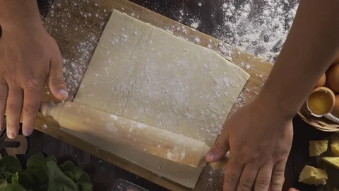 Flat lay shot: chef rolls out the dough with a rolling pin on the kitchen table Stock Footage 114562151