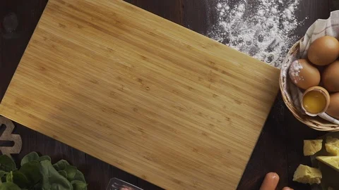 Flat lay shot: chef sprinkles flour to the wooden board before rolling out the Stock Footage 114563206