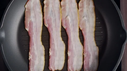 Flat lay shot of pieces of bacon being roasted on the hot grill pan, slow motion Video stock 114011147