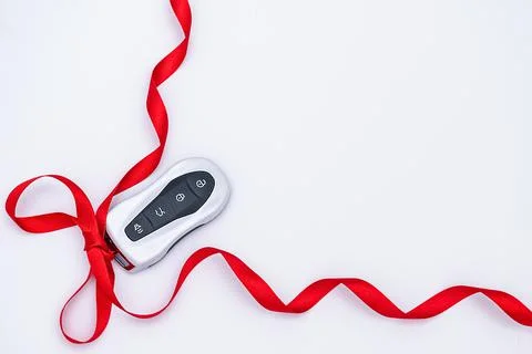 Flat lay smart car key with a red gift ribbon on a white background. Electron Stock Photos