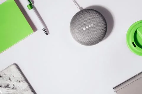 Flat lay of smart speaker with LED lights activated with cropped smartphone Stock Photos