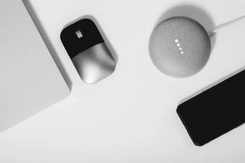 Flat lay of smart speaker with LED lights activated, laptop, mouse and Stock Photos